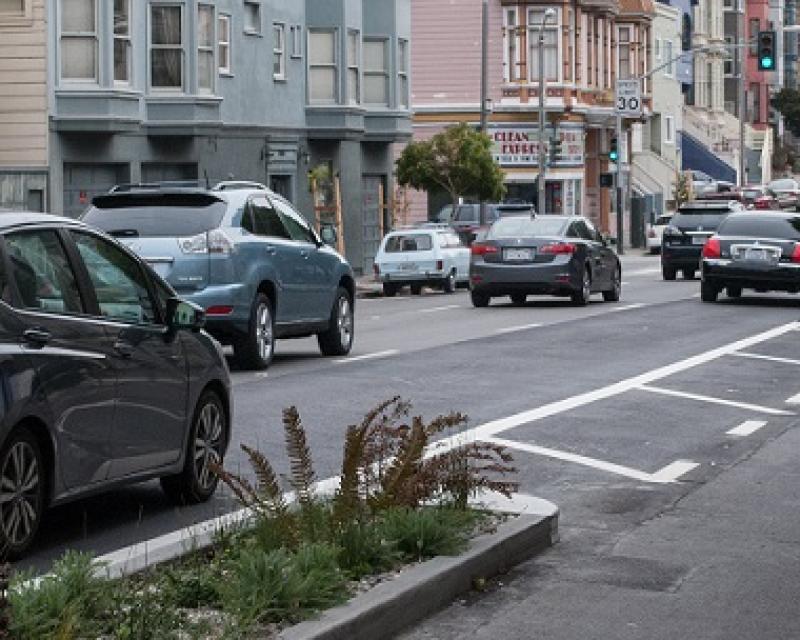 Bikes and cars traveling down the street.