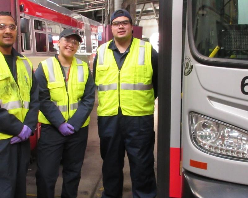 Shop workers beside a bus.
