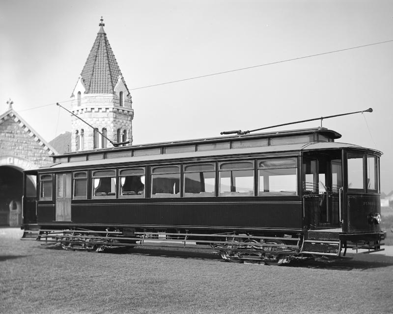 Funeral streetcar at cemetery with stone building in background