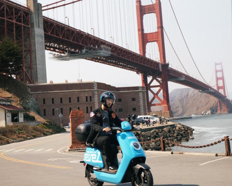 A user rides their Revel shared electric moped at Fort Point