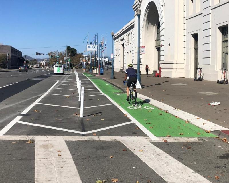 Person riding their bike past the Ferry Building on the green bike path