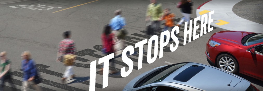 Campaign ad image featuring the text "It Stops Here" and an intersection with cars next to pedestrians using a crosswalk.