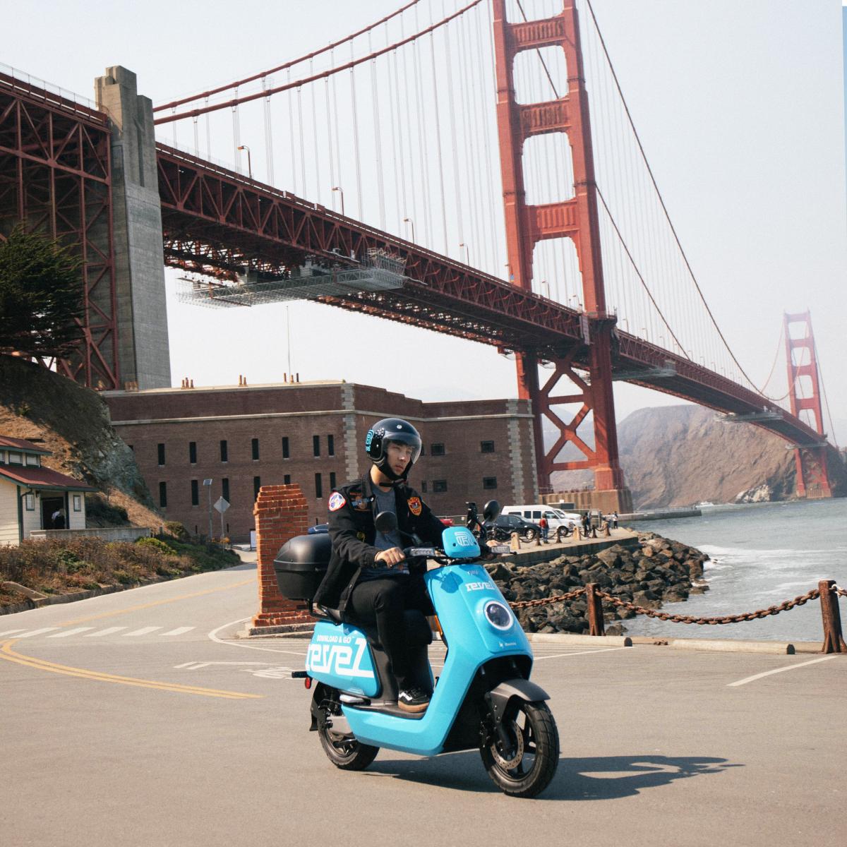 A Revel user rides a shared electric moped in front of Fort Point